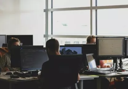 Several people work in an open space, each in front of his or her own computer.
